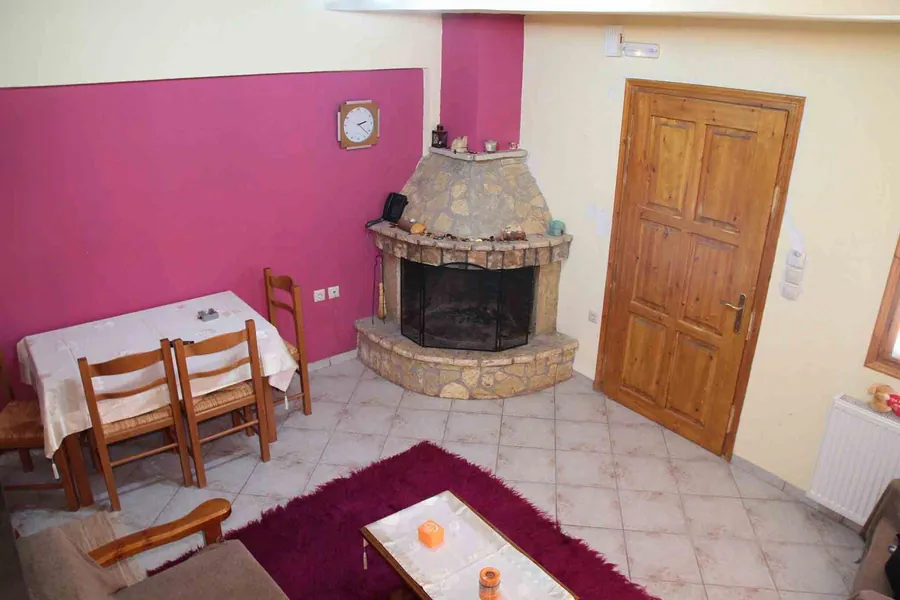 Σαλόνι με πέτρινο γωνιακό τζάκι, τραπεζαρία και ξύλινη πόρτα